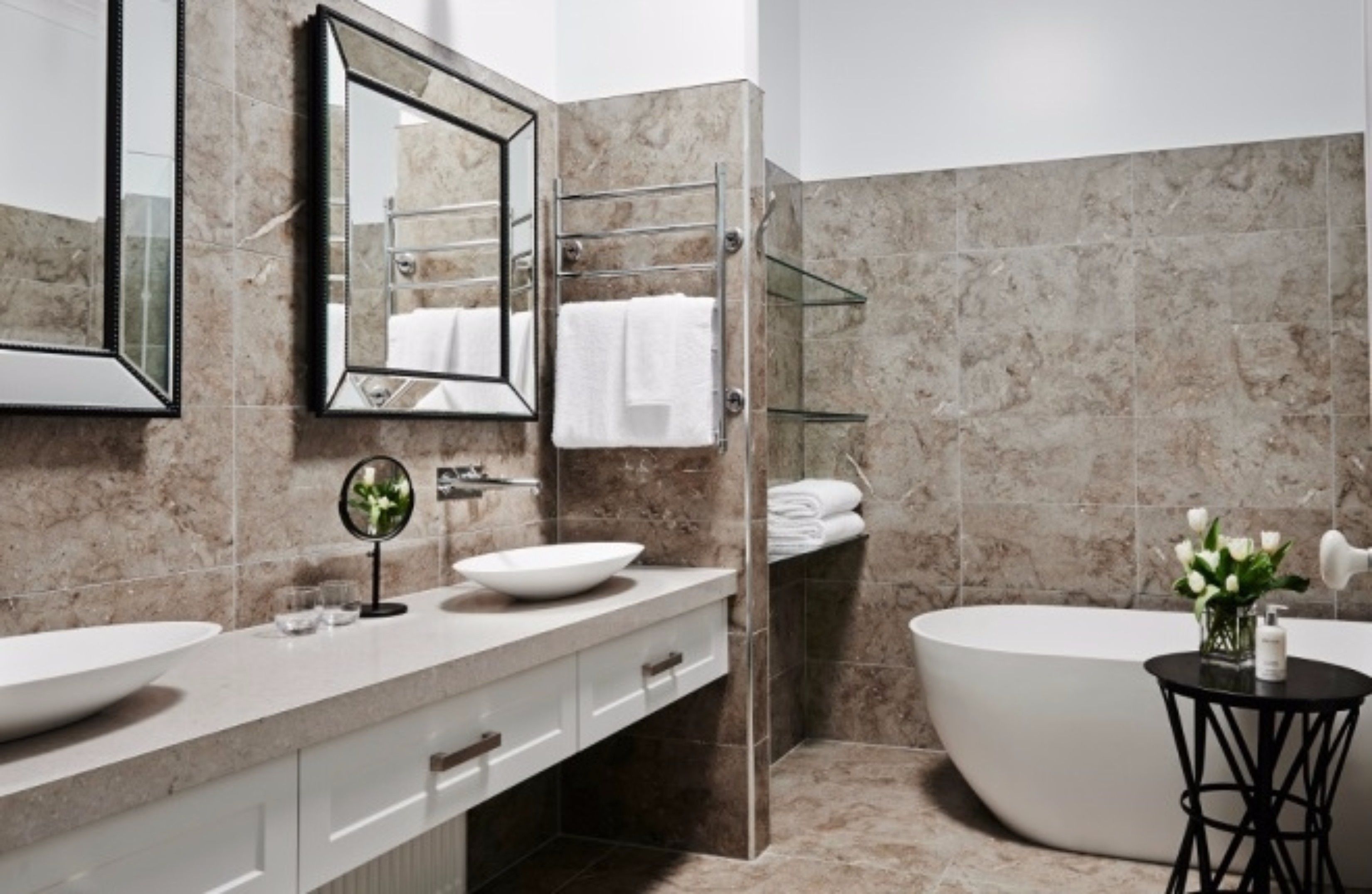 A modern bathroom with a freestanding bathtub, a large mirror, a vanity with a bowl sink, and a glass shower enclosure.
