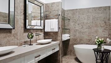 A modern bathroom with a freestanding bathtub, a large mirror, a vanity with a bowl sink, and a glass shower enclosure.