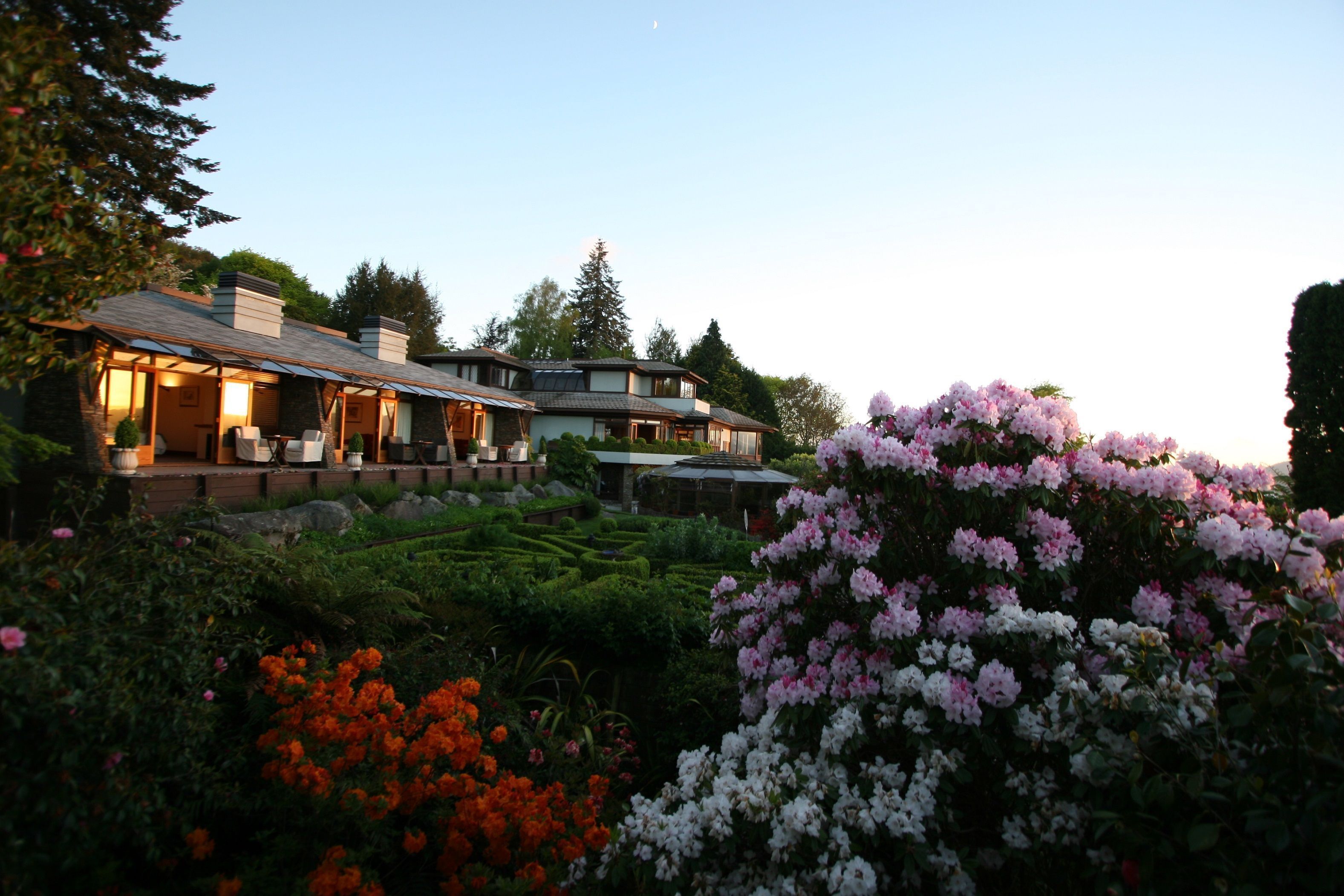 A large, multi-story house with a well-maintained garden and outdoor seating area.