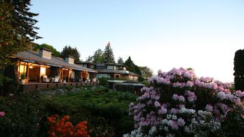 A large, multi-story house with a well-maintained garden and outdoor seating area.