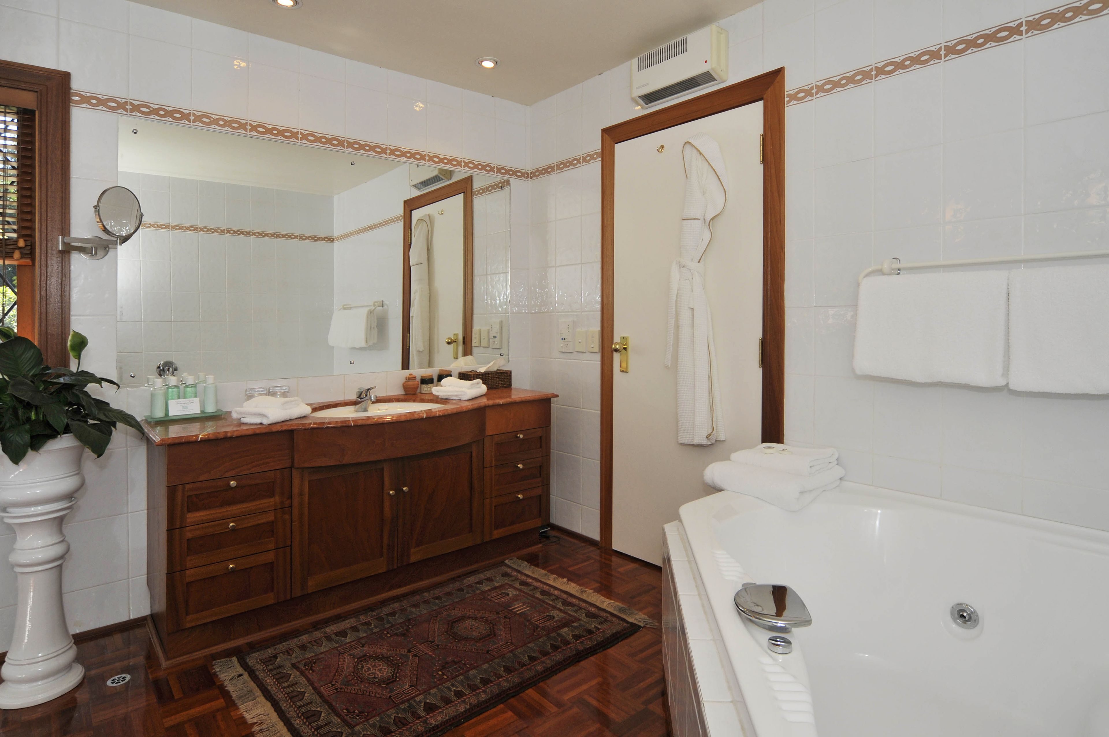 A bathroom with a wooden vanity, a large mirror, a bathtub, and a shower.