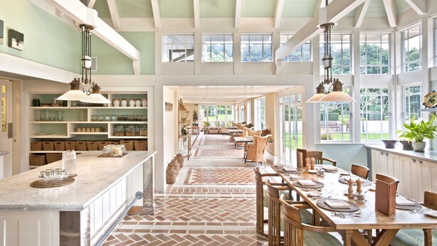 Una cocina amplia con una barra desayunadora grande, mucho espacio de almacenamiento y ventanas grandes que ofrecen vistas al exterior.
