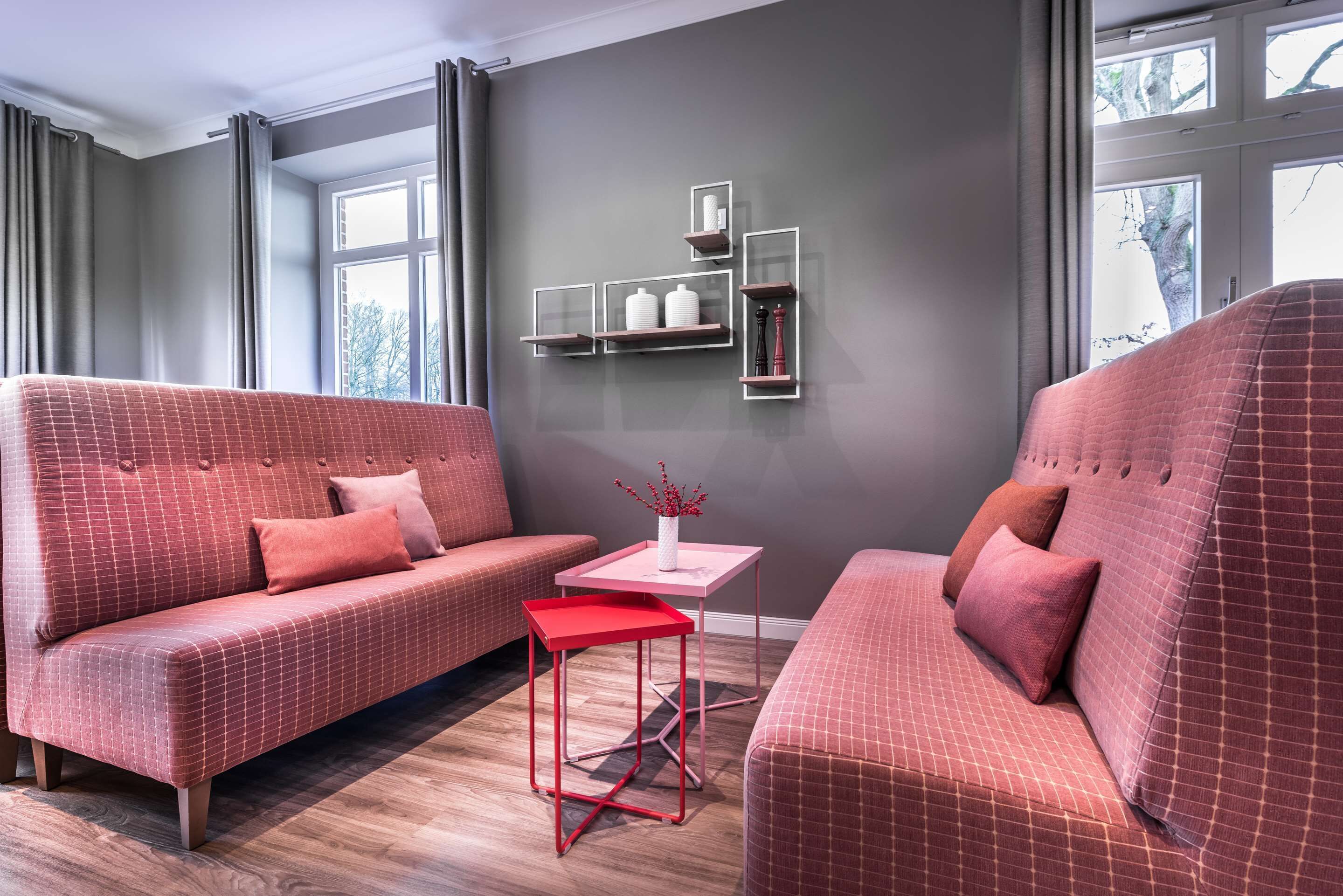Een moderne woonkamer met twee banken, een klein tafeltje en inbouwkasten tegen een grijze muur.