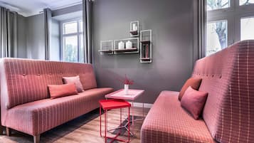 Een moderne woonkamer met twee banken, een klein tafeltje en inbouwkasten tegen een grijze muur.