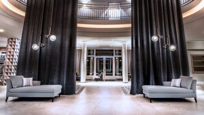A spacious lobby with a curved ceiling, two sofas, and a staircase leading to an upper level. - Steigenberger Hotel Treudelberg Hamburg (Hamburg)