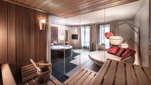 Ein modernes Hotelzimmer mit Holzboden, einer großen runden Badewanne, einer Couch mit roten Kissen und einem Esstisch.