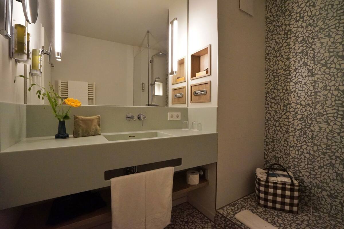 A modern bathroom with a large mirror, a sink, and a shower.