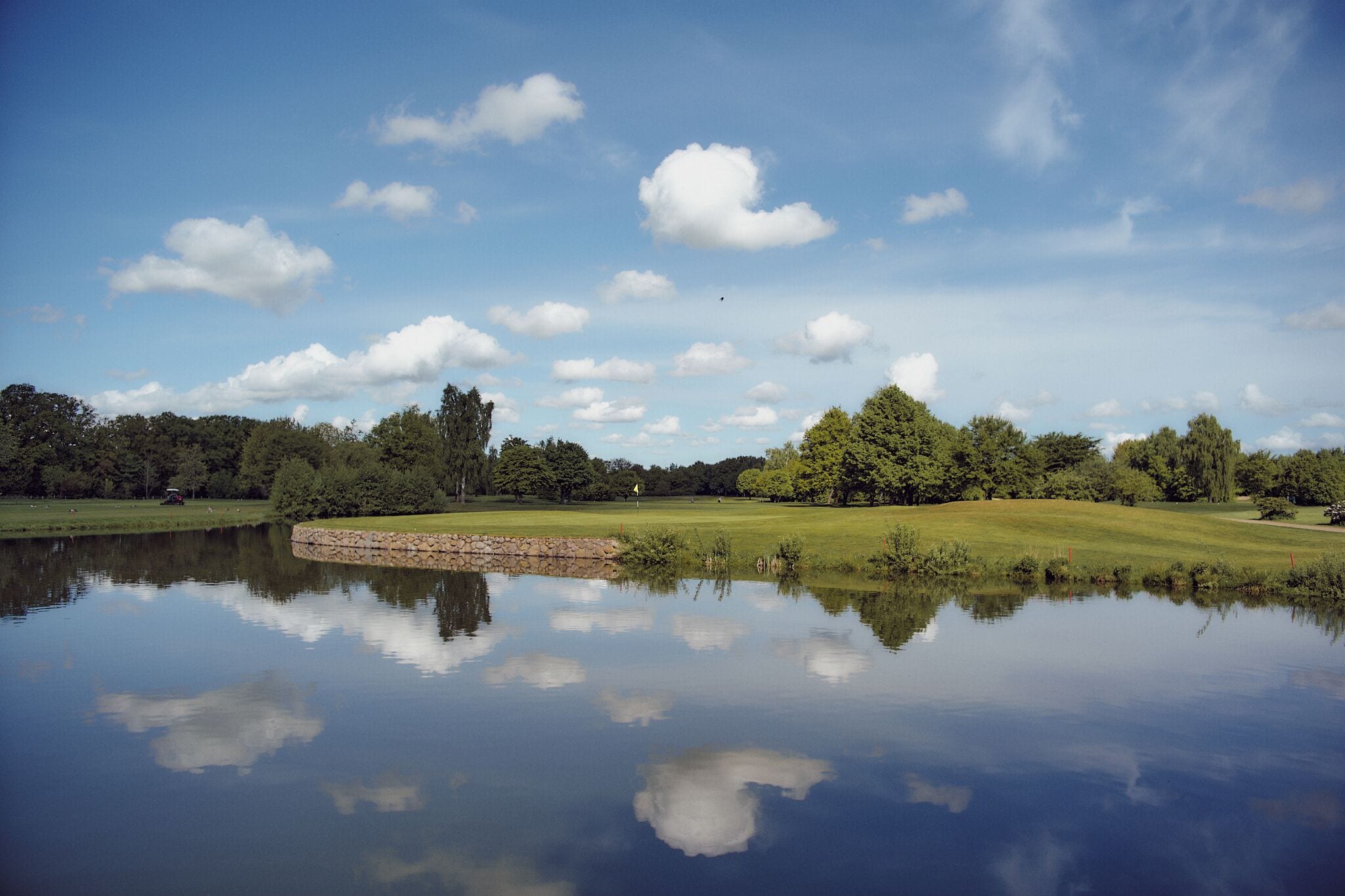 Een rustig landschap met een kalm meer dat de lucht en bomen weerspiegelt.