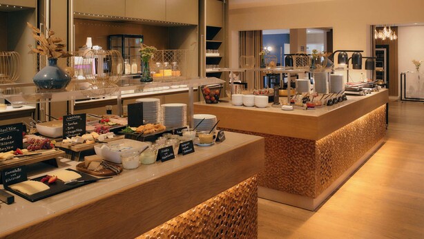 A buffet setup with various food items and serving utensils. - Steigenberger Hotel Treudelberg Hamburg (Hamburg)