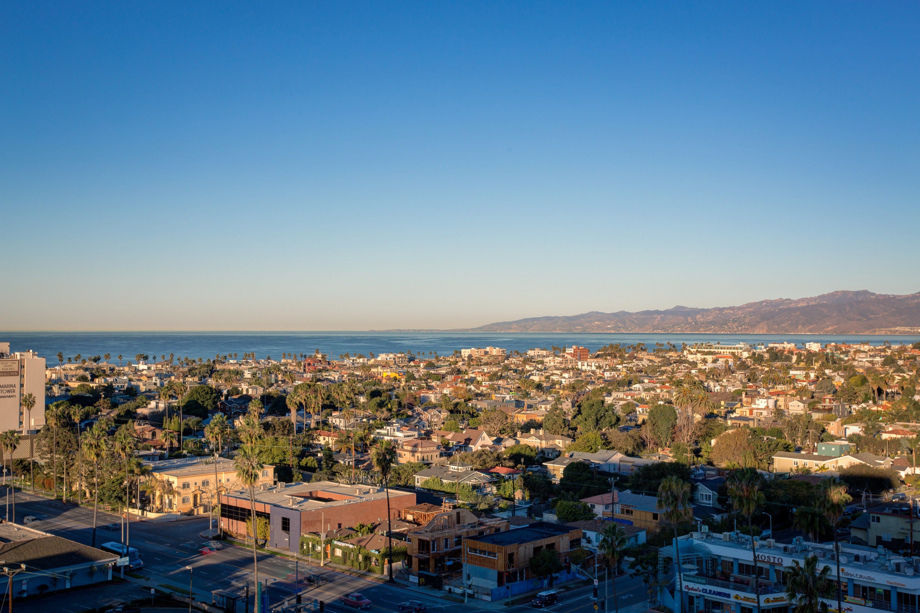 A coastal cityscape with a view of the ocean and mountains in the distance.