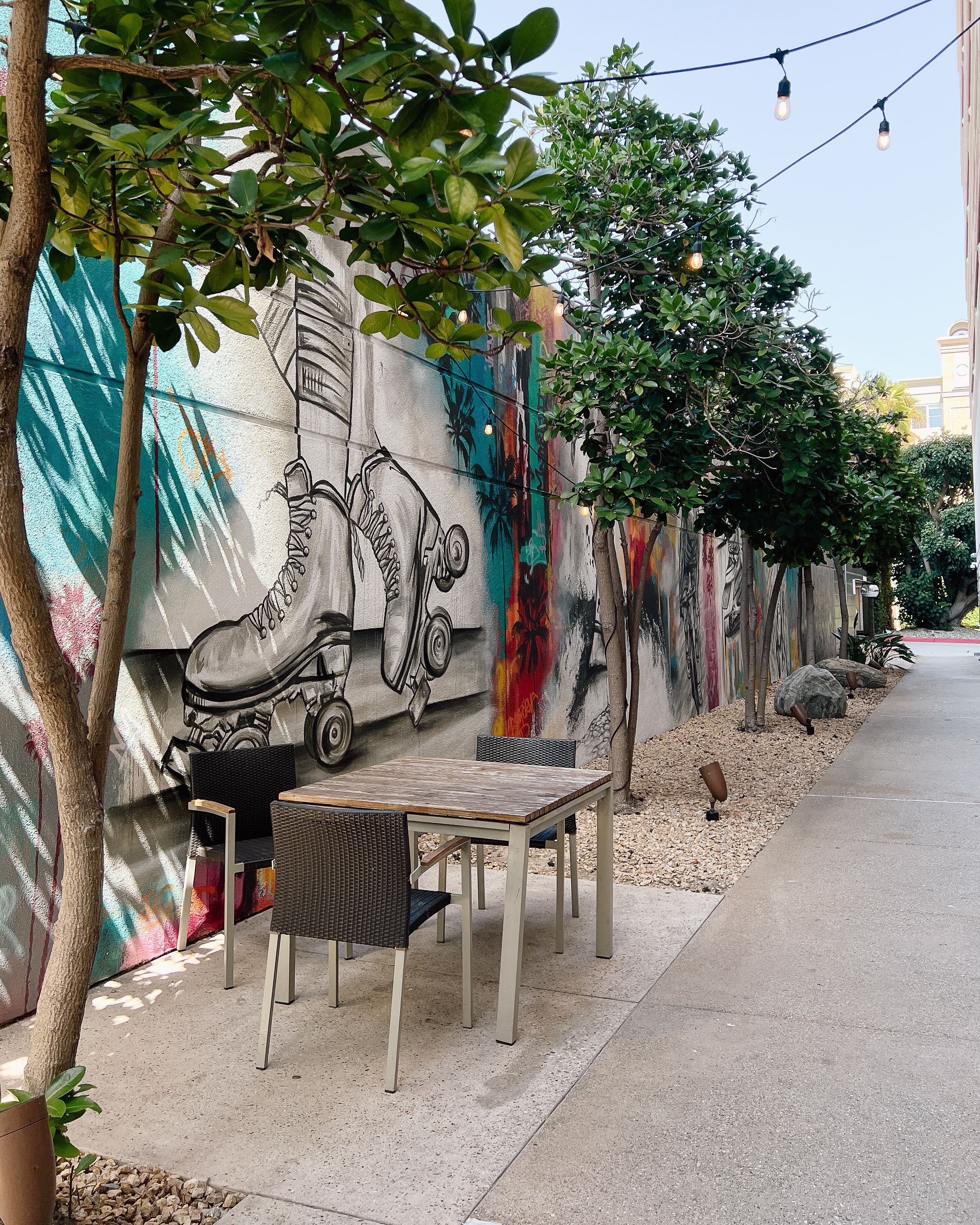 A dining area with a mural, outdoor seating, and string lights.