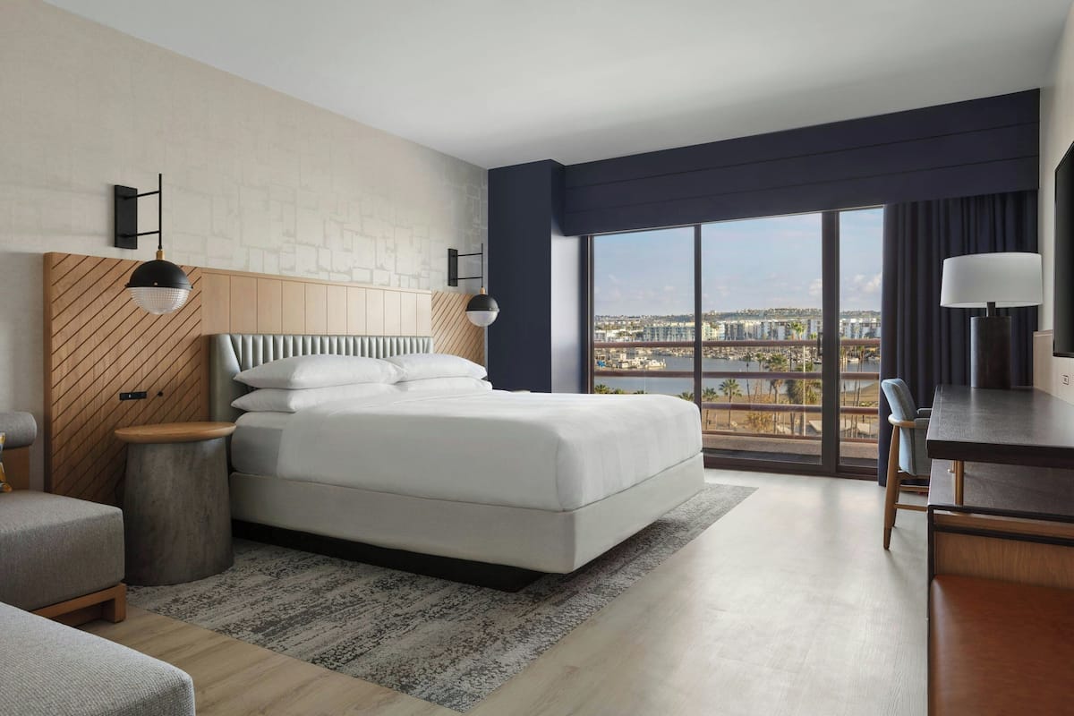 Habitación de hotel moderna con una cama grande, un escritorio y vistas a la ciudad.