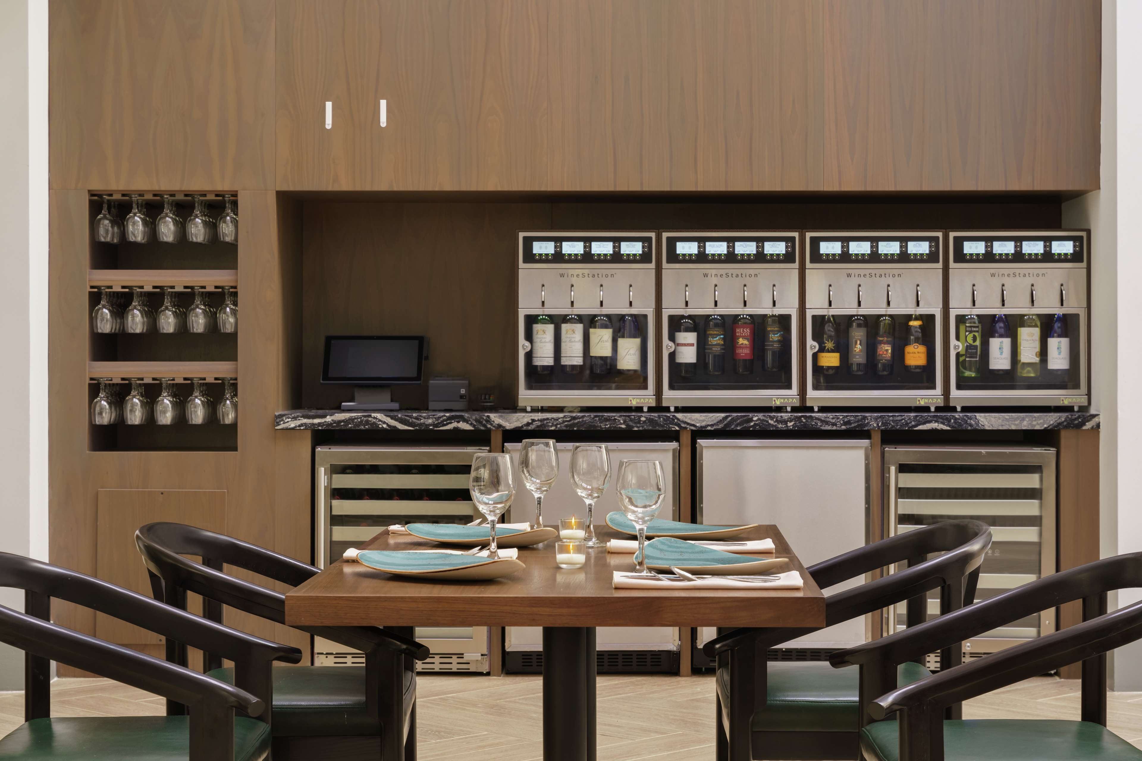 A restaurant with a wooden interior, a marble countertop, and a wine station with multiple bottles.