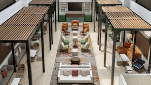 A modern lounge area with a central sofa, multiple seating options, and a herringbone floor pattern. - Embassy Suites by Hilton Philadelphia Valley Forge (Wayne)