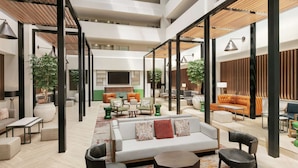 A spacious, multi-level hotel lobby with a variety of seating options, including sofas, chairs, and a coffee table. - Embassy Suites by Hilton Philadelphia Valley Forge (Wayne)