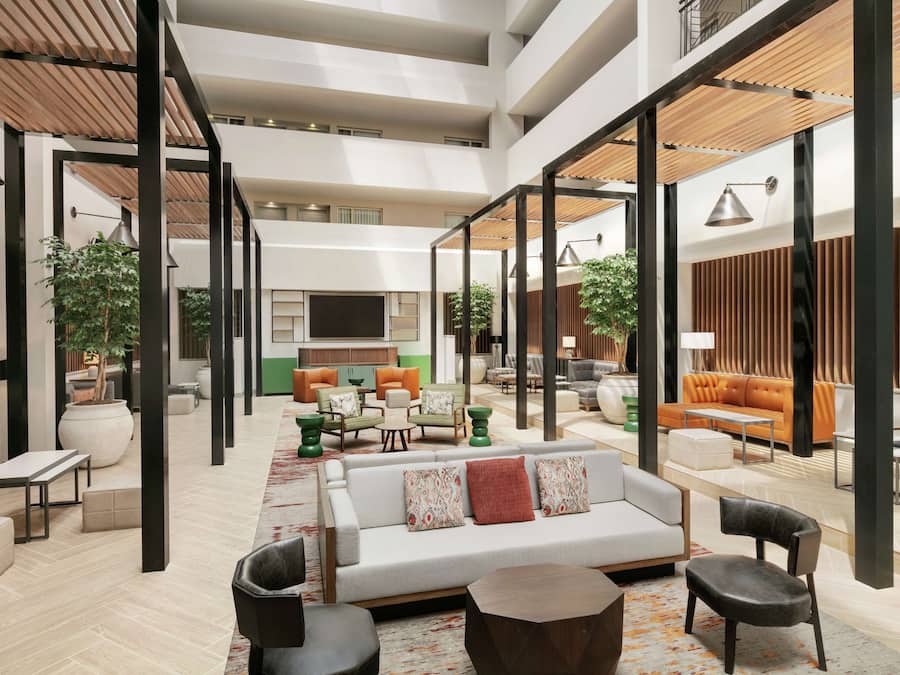 En rymlig hotellobby i flera våningar med olika typer av sittplatser, inklusive soffor, fåtöljer och ett soffbord.