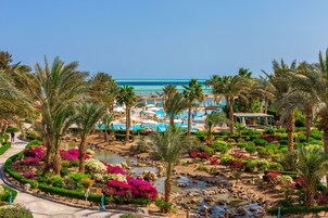 A resort with a pool area, palm trees, and a water feature.