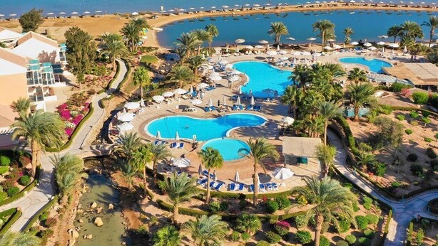 A resort with multiple swimming pools, palm trees, and a beach.