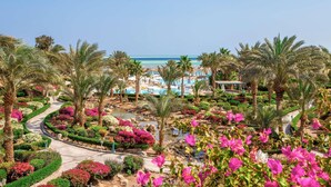 A resort with a pool, palm trees, and a view of the beach.