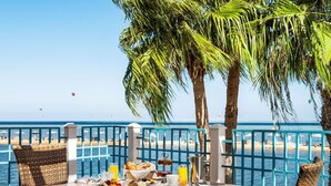 A dining table with breakfast items, wicker chairs, and a view of the ocean.