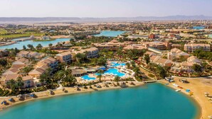 A resort with multiple swimming pools, beachfront, and a variety of building styles.
