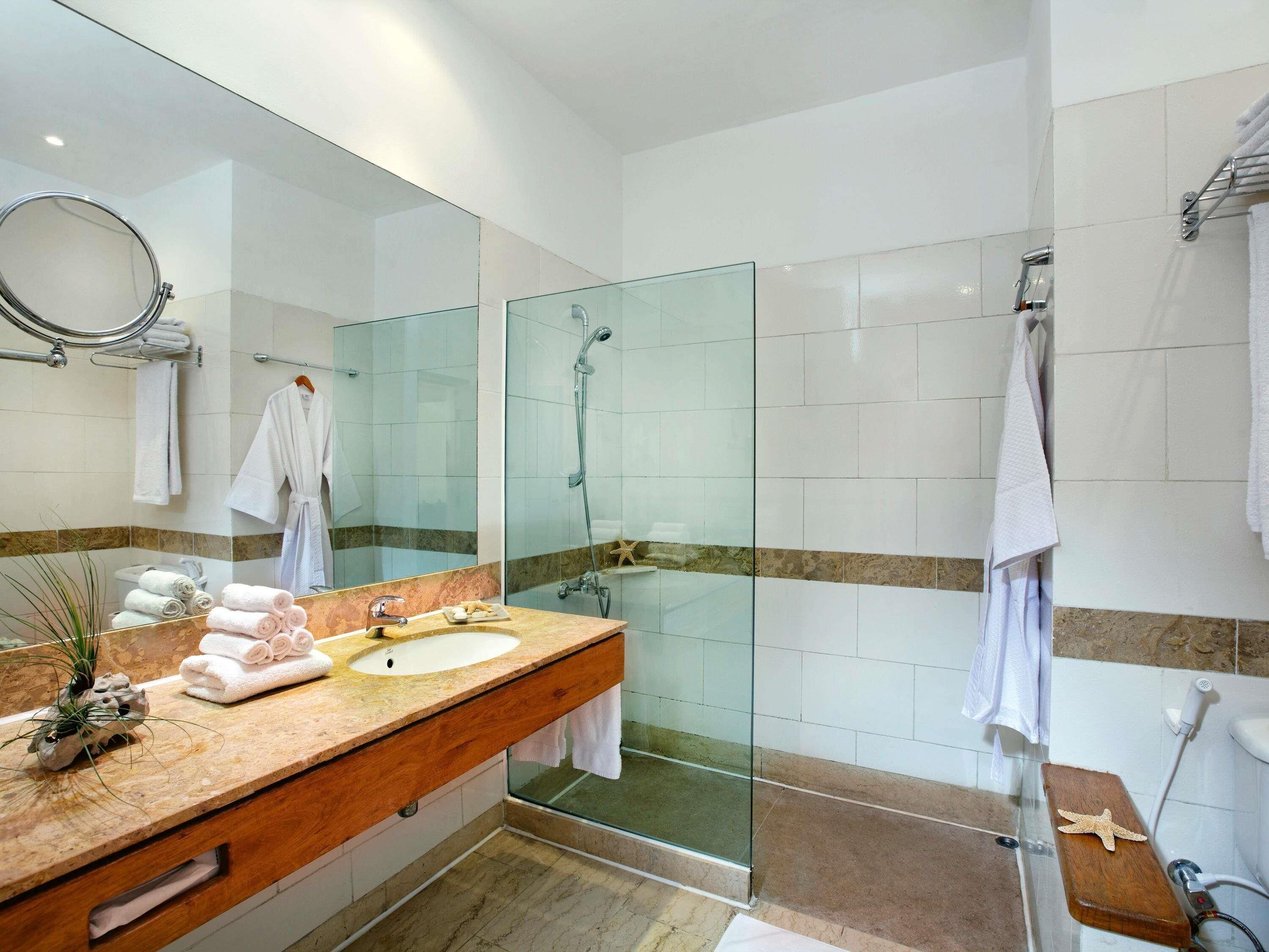 A modern bathroom with a glass shower enclosure, a vanity with a sink, and multiple towels.