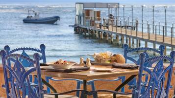 A dining table with chairs and a view of the sea and a pier.