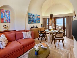 A modern living room with a red sofa, a dining area with wicker chairs, and a view of the ocean.