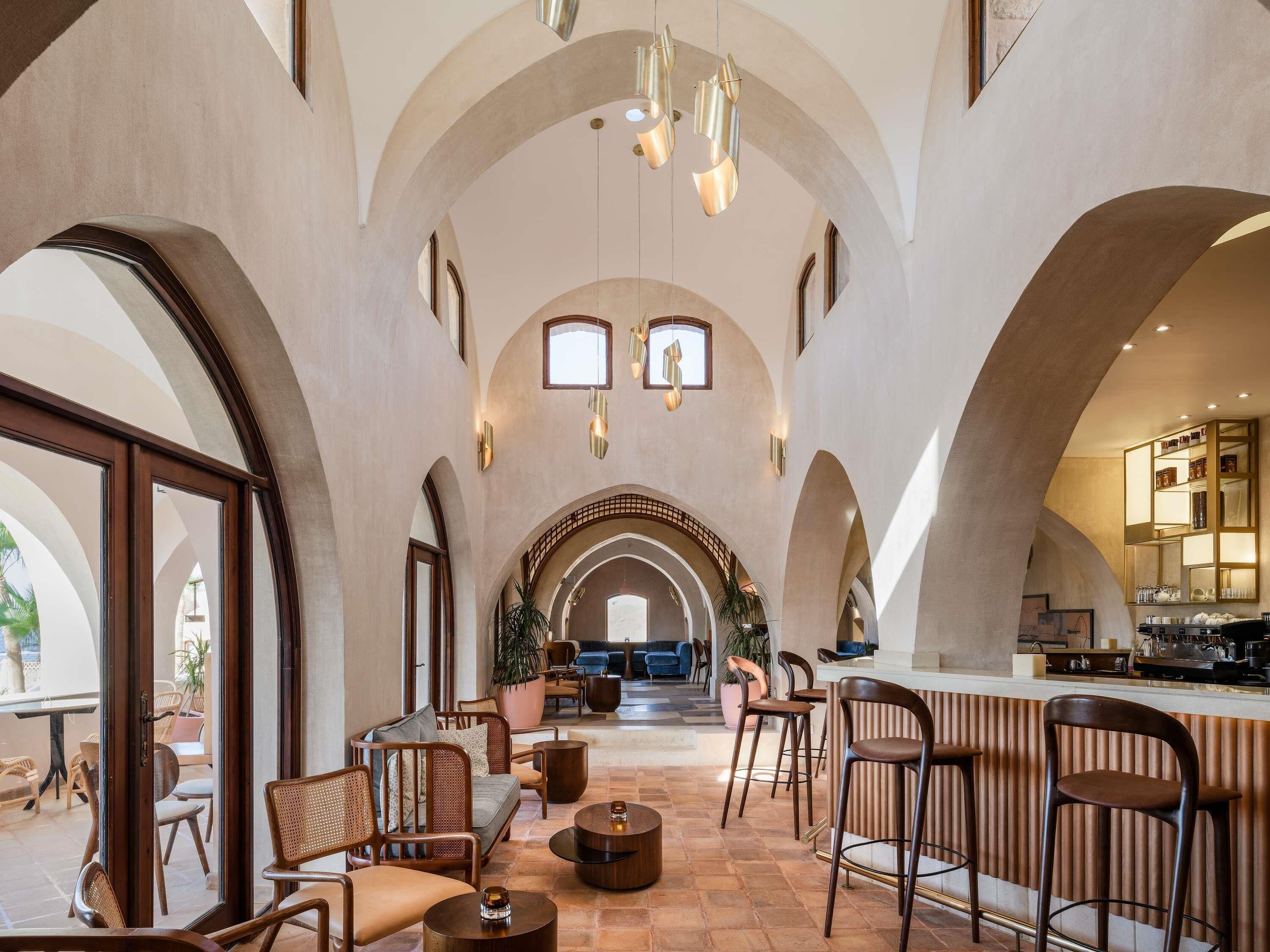 A spacious interior with arched ceilings, a bar area, seating, and a view through large windows.