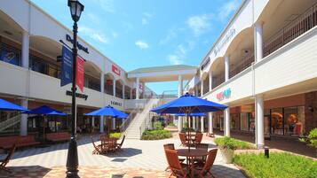 Un centro comercial con zonas de estar al aire libre, una escalera y diversas tiendas.