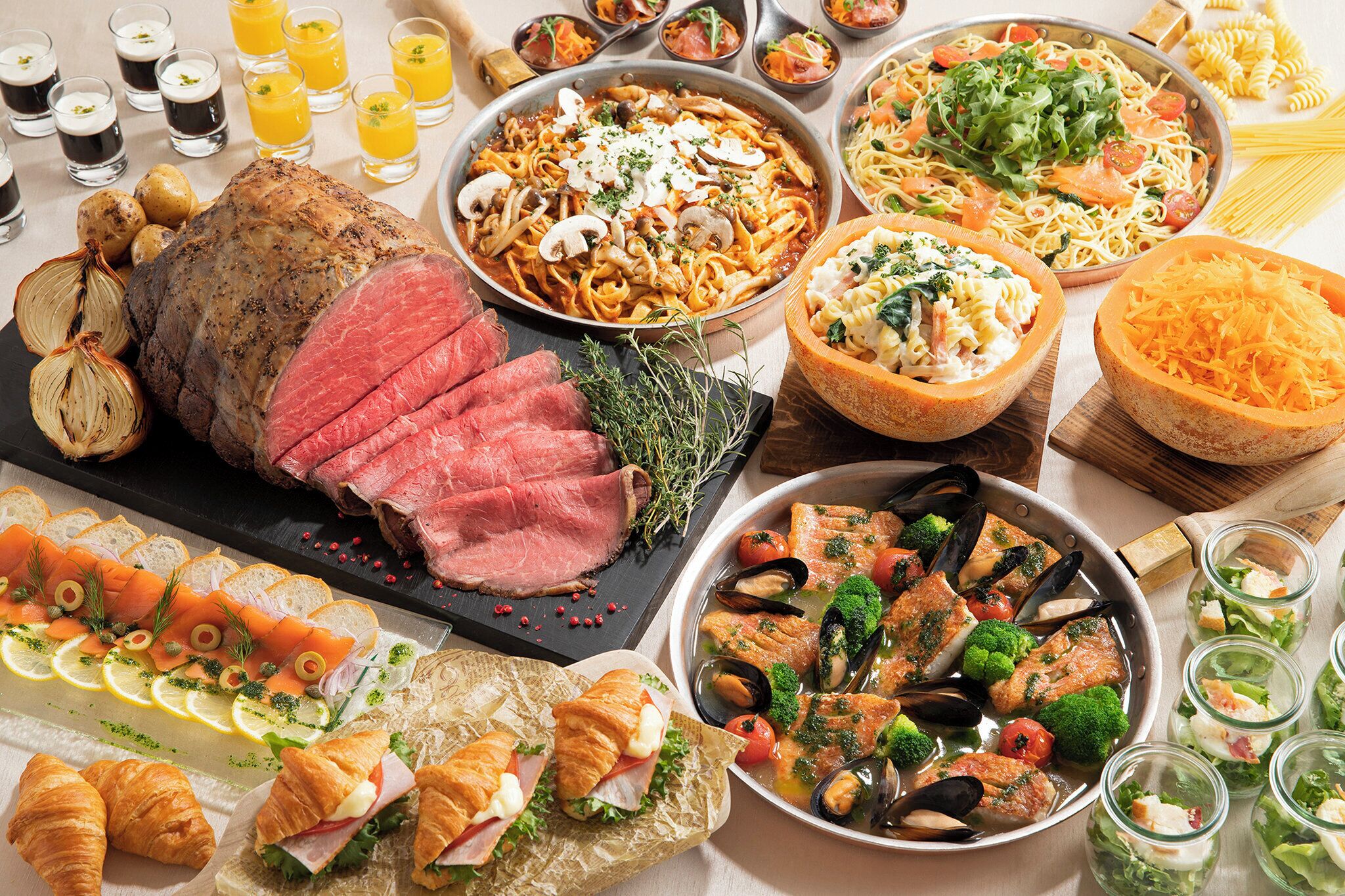A variety of dishes including a roasted meat centerpiece, pasta, seafood, and salads.