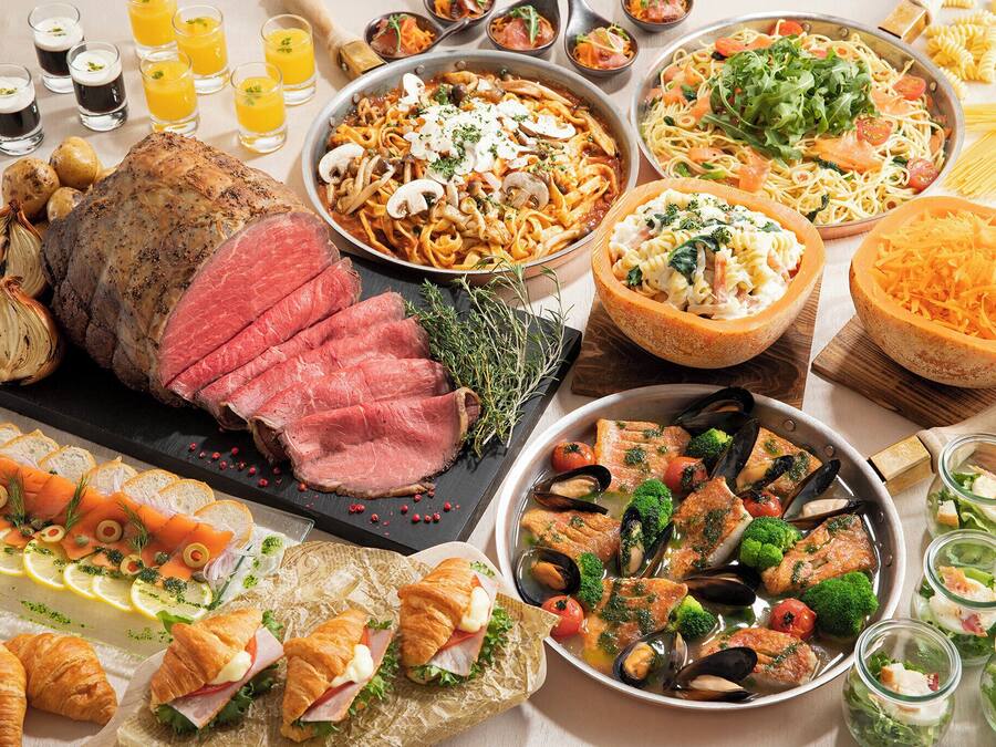 A variety of dishes including a roasted meat centerpiece, pasta, seafood, and salads.