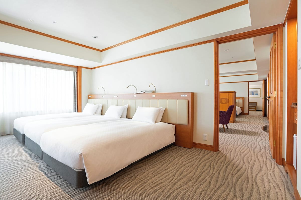 A hotel room with a large bed, a wooden headboard, and a carpeted floor.
