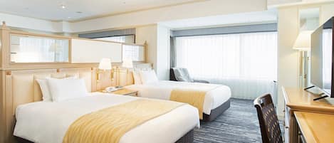 A hotel room with two beds, a desk, a chair, a TV, and a window with curtains.