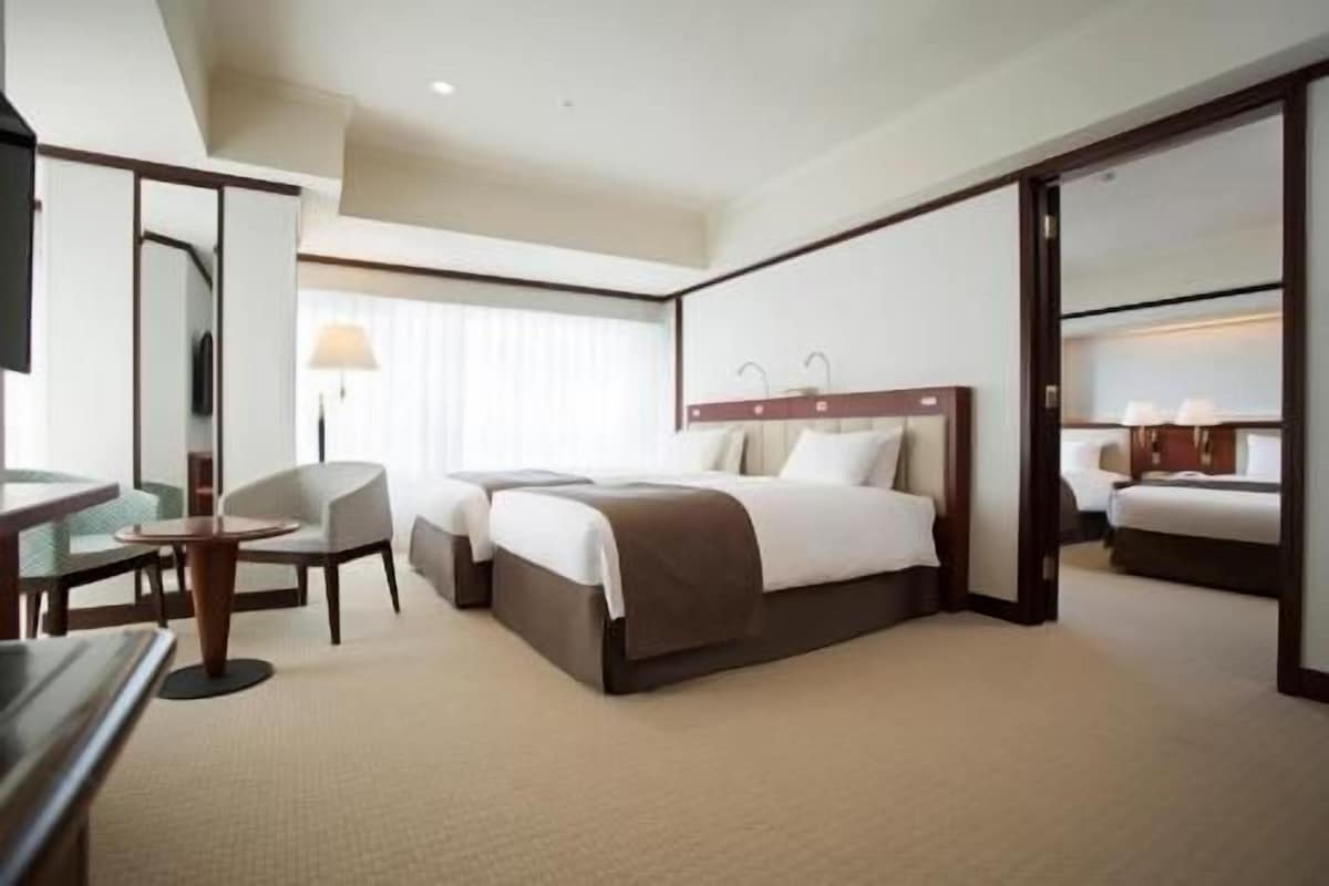 A hotel room with a large bed, a desk, a chair, and a mirror.