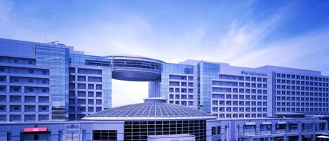 Un hotel moderno con una fachada de vidrio curvo distintiva, un atrium central y un jardín en la azotea.