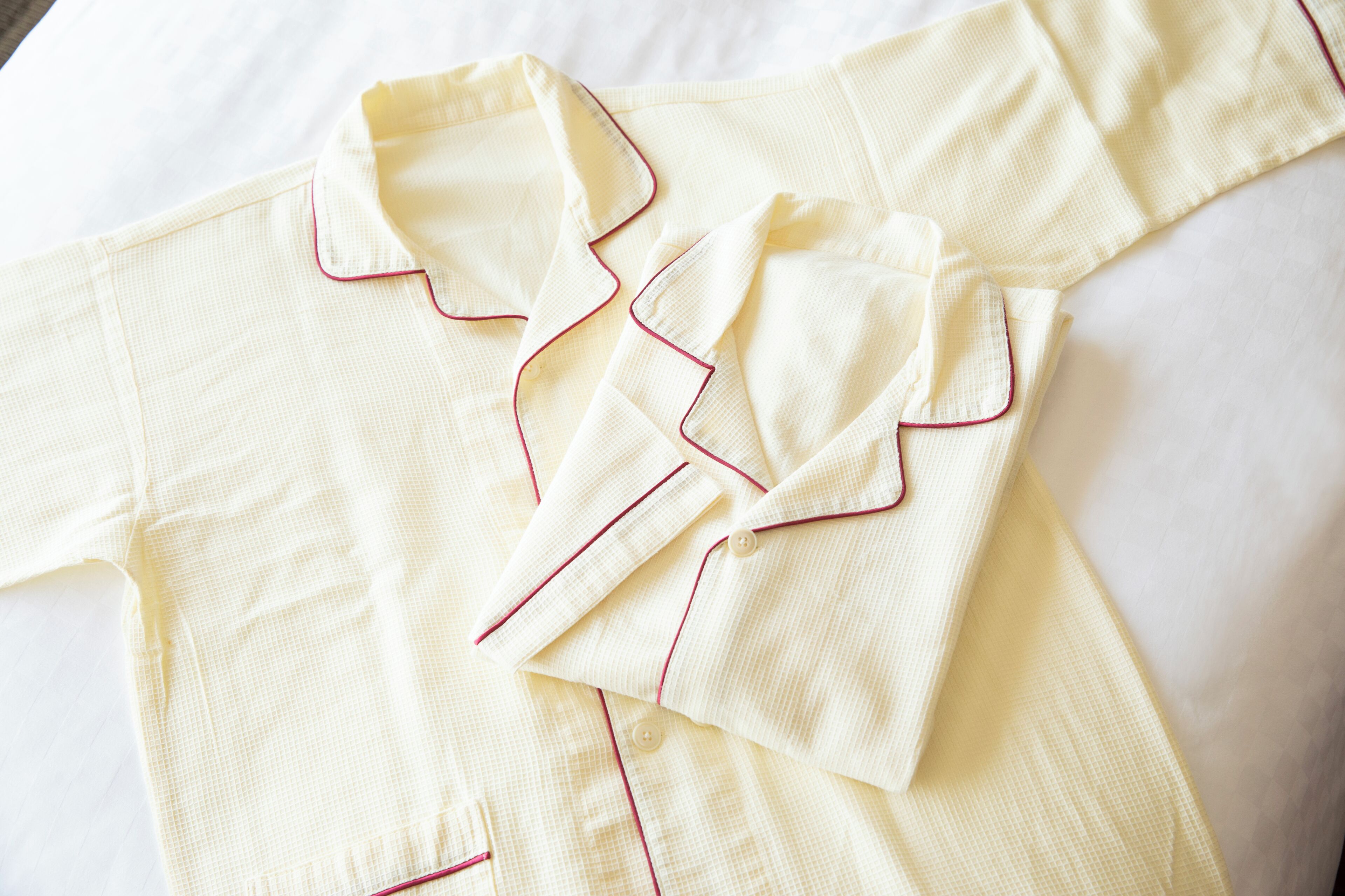 Una camisa blanca impecablemente doblada con detalles rosados.