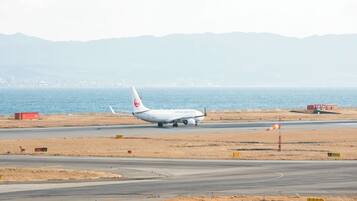 A Japan Airlines airplane on a runway with dry grass fields and mountains in the background.