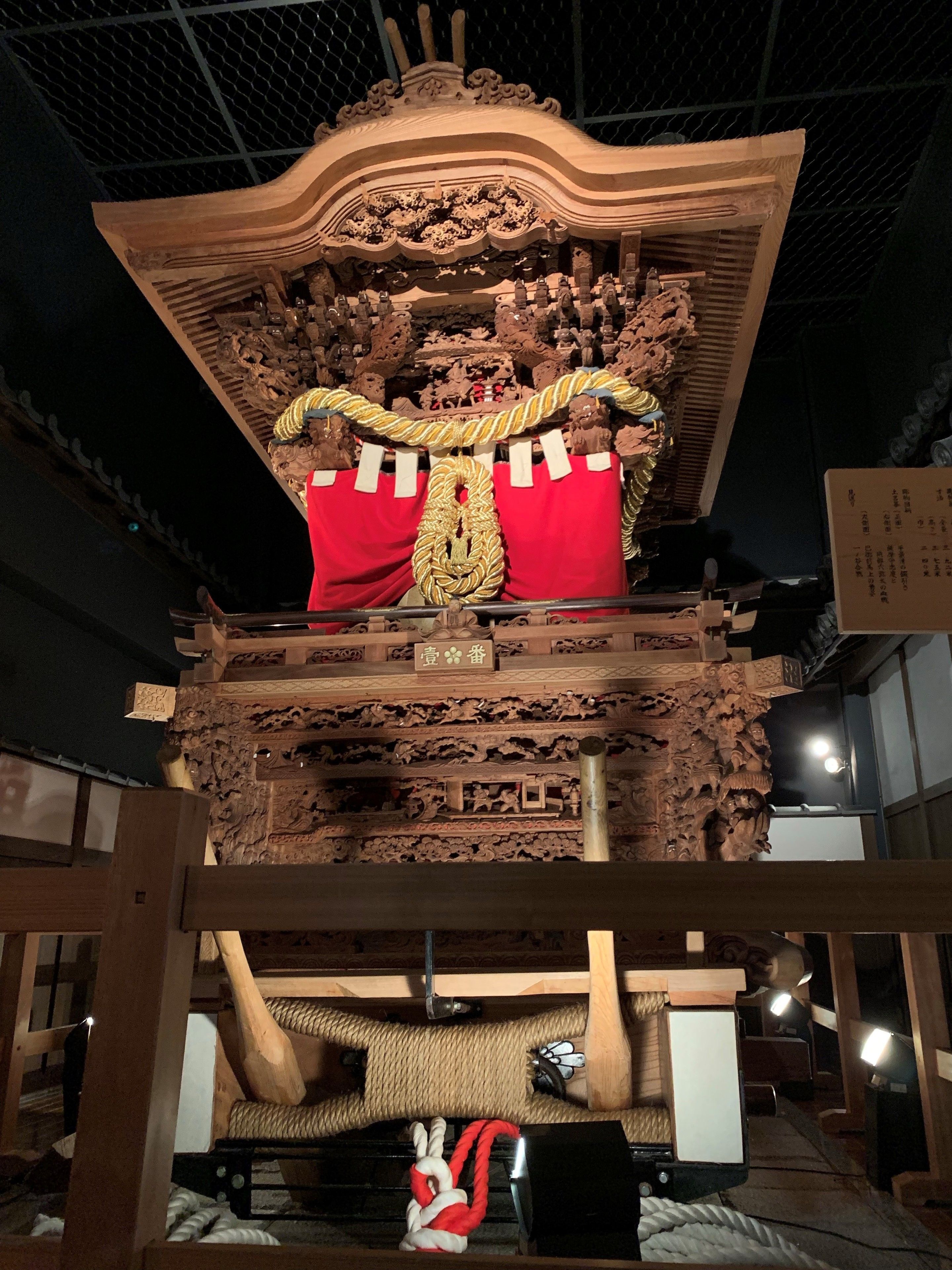 Eine traditionelle Holzhütte mit aufwendigen Schnitzereien und roten sowie goldenen Verzierungen.