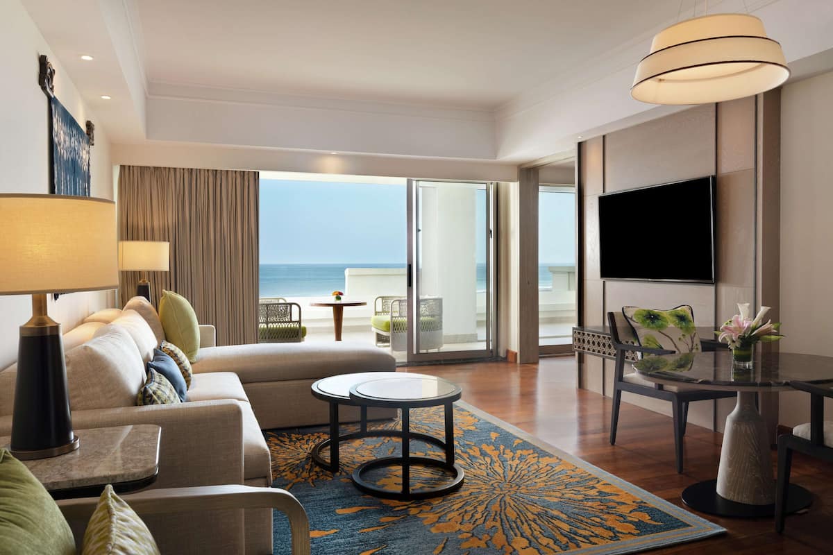 Ein modernes Hotelzimmer mit einer Couch, einem Couchtisch, einem Fernseher und einem Balkon mit Meerblick.