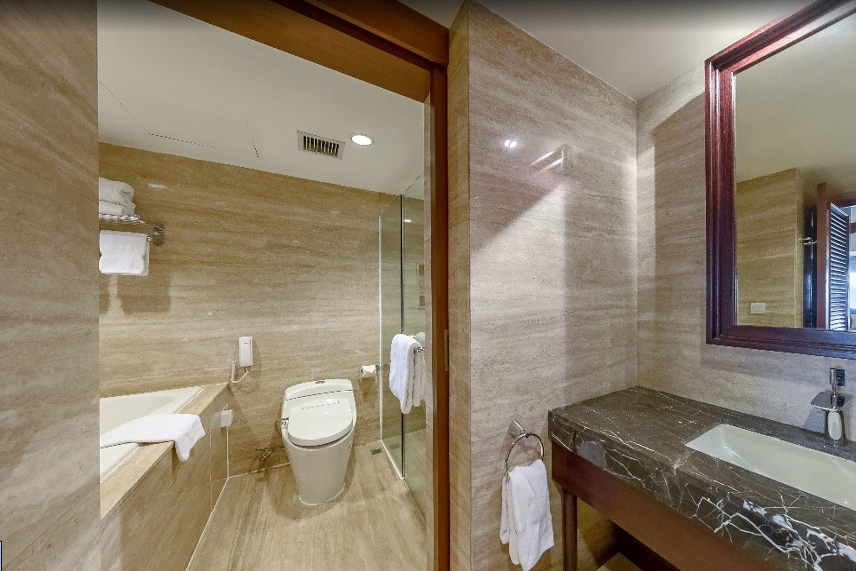Ein modernes Badezimmer mit Marmor-Waschtisch, einer Duschkabine aus Glas und einem großen Spiegel.