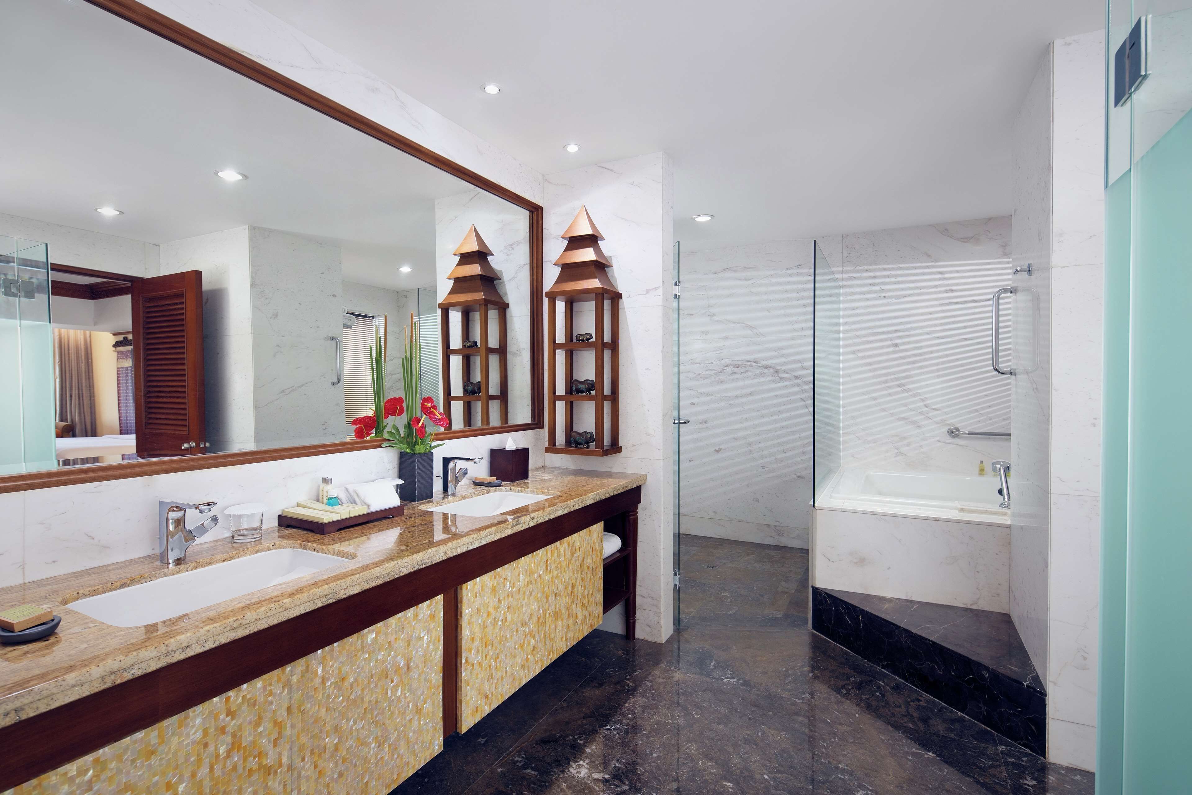 A modern bathroom with a dual sink vanity, a large mirror, and a glass-enclosed shower.