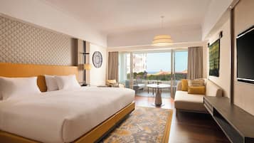 A hotel room with a large bed, a sofa, a TV, and a balcony with a view.