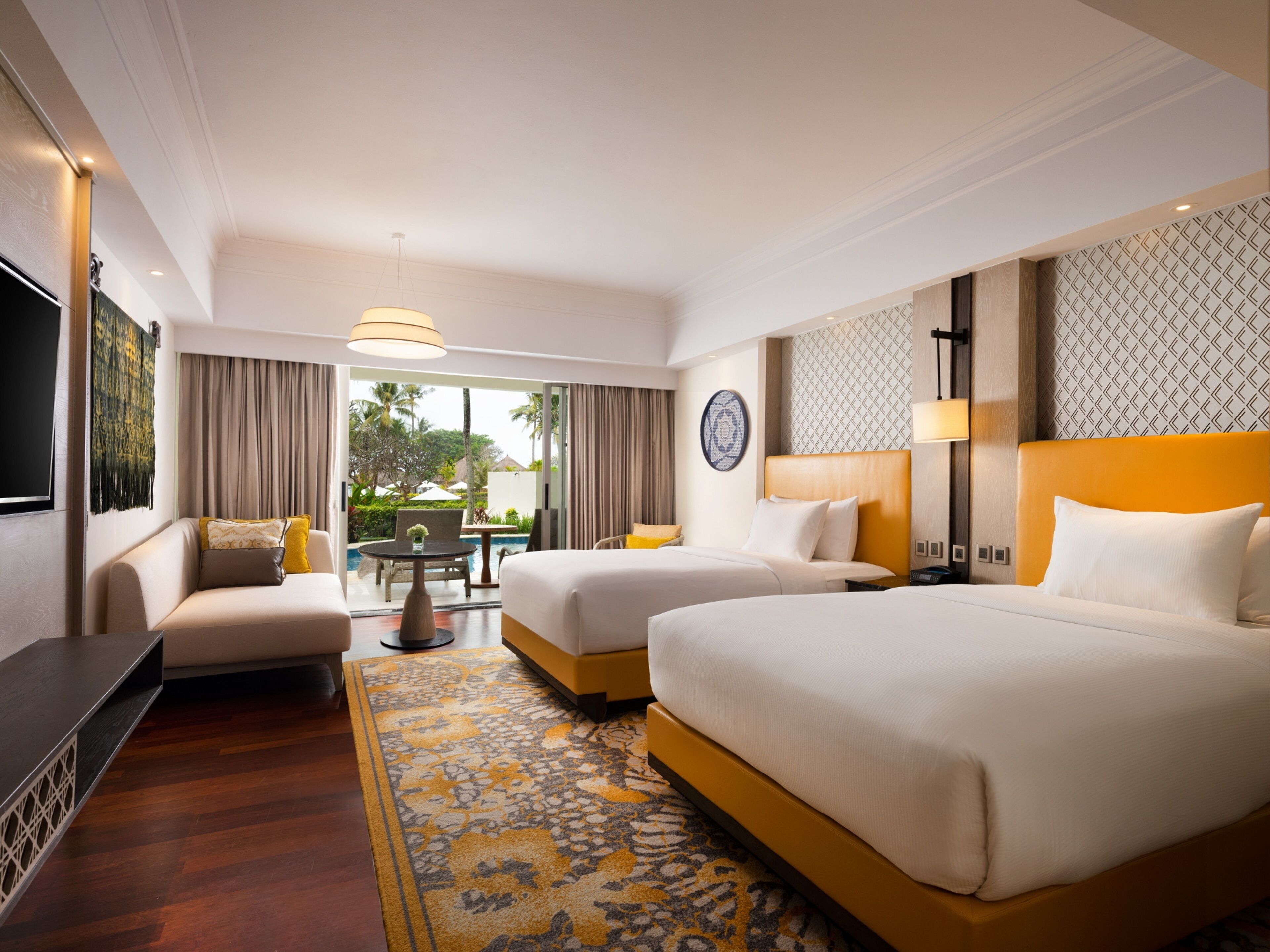 A hotel room with two beds, a sofa, a TV, and a view of the outdoors.