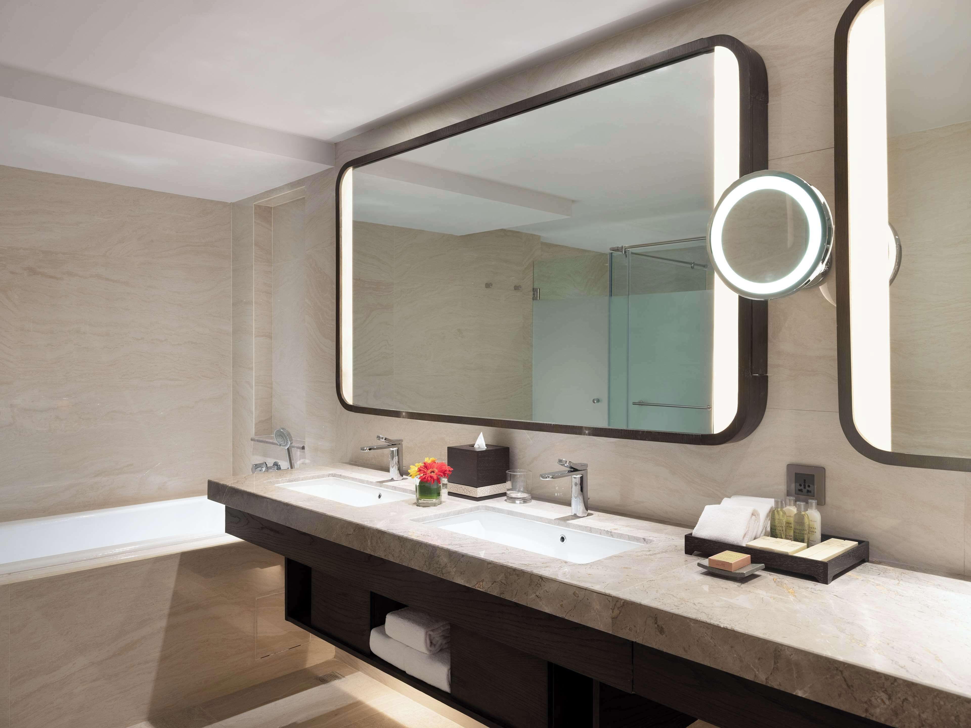 Un bagno moderno con due lavabi, uno specchio grande e un box doccia in vetro.