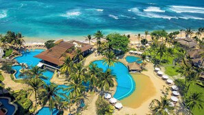 An aerial view of a resort with multiple swimming pools, a beach, and palm trees. - Hilton Bali Resort (Nusa Dua)