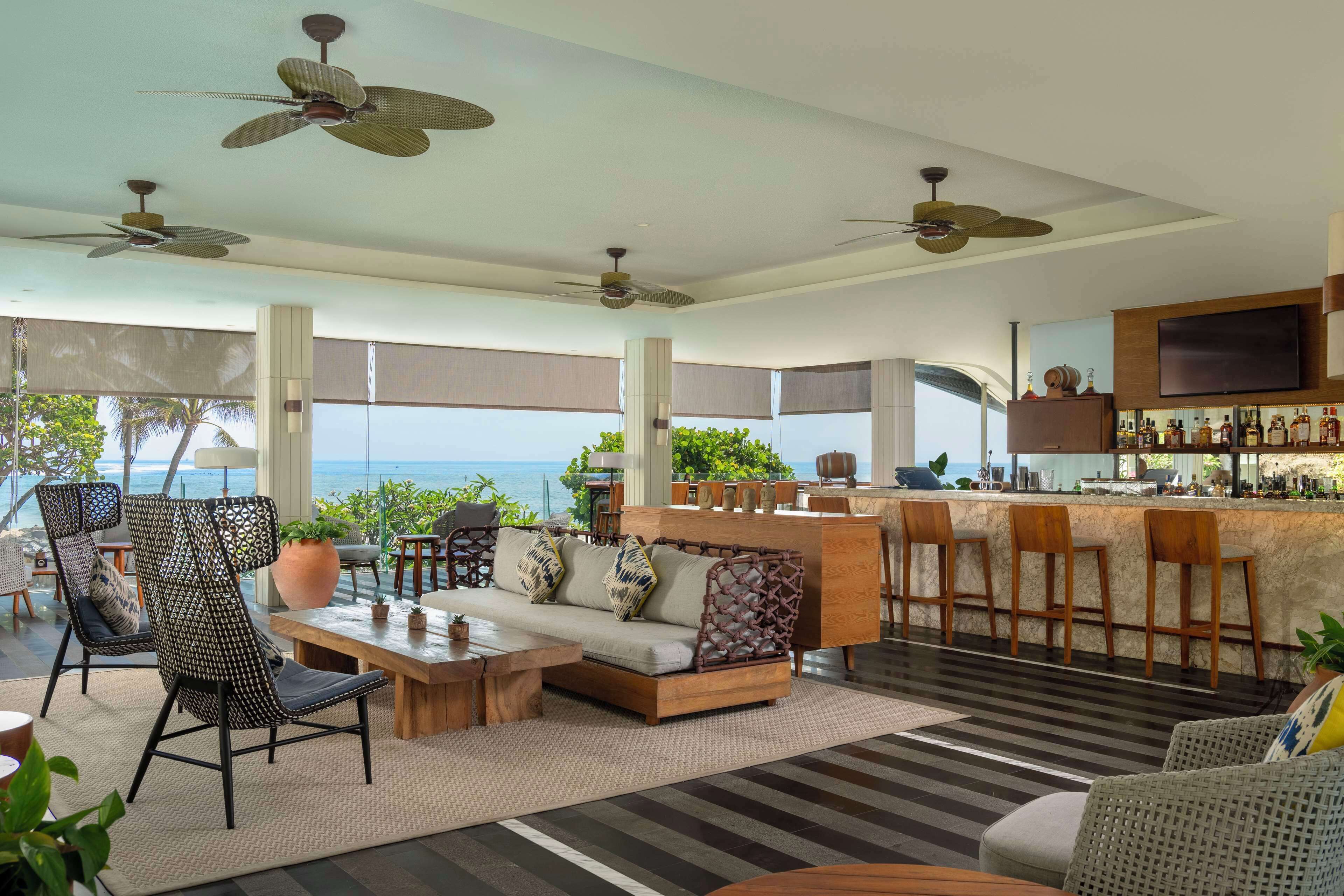 A spacious living area with a sofa, chairs, a coffee table, and a bar area with stools.