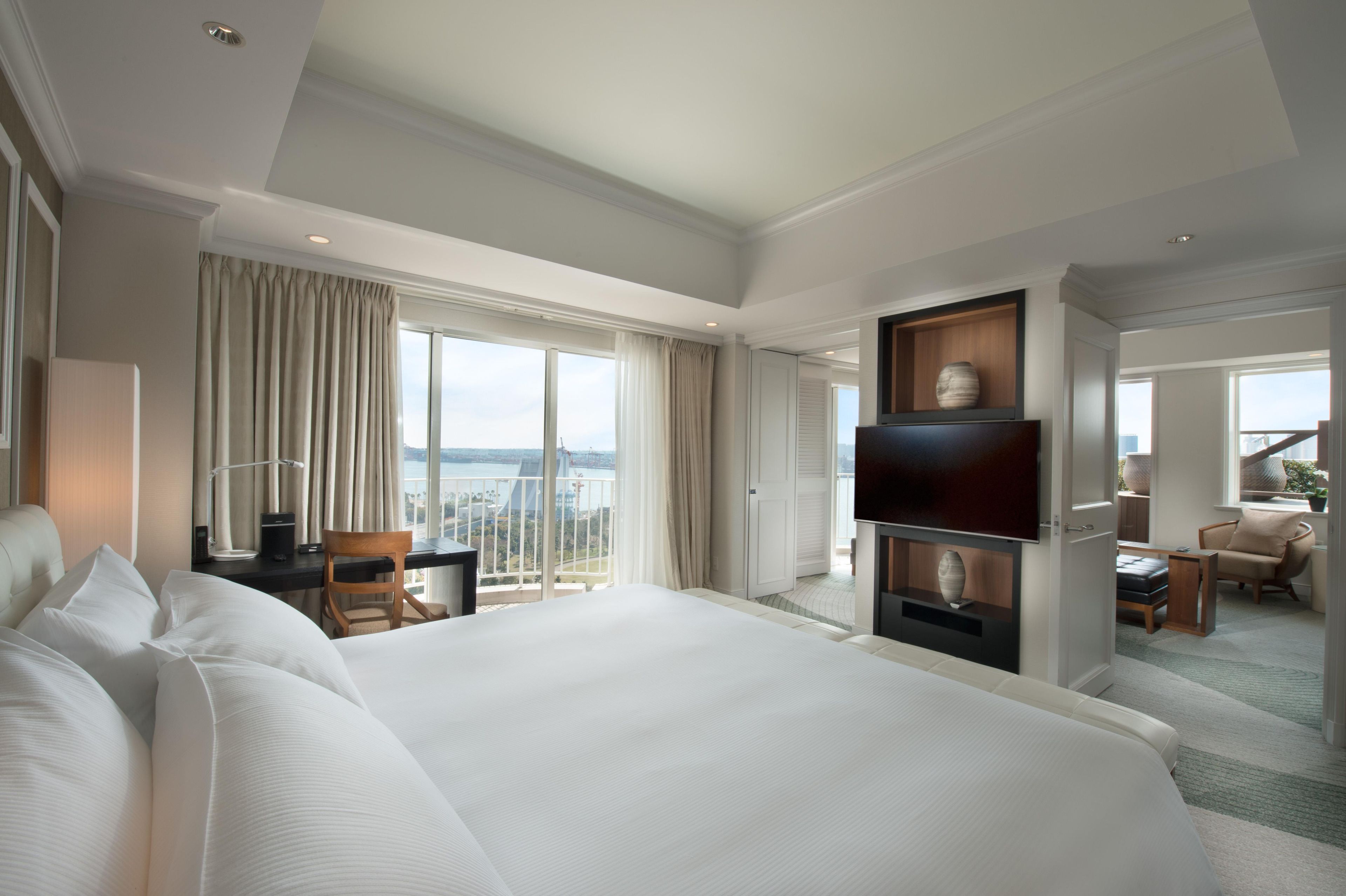 Una habitación de hotel con una cama grande, un escritorio, una silla, un televisor y vistas a la ciudad.