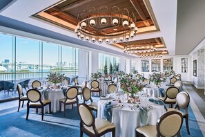 A dining area with round tables, chairs, and a city view. - Hilton Tokyo Odaiba (Tokyo)