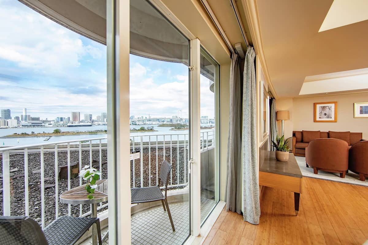 A balcony with a view of a cityscape, a dining area with a table and chairs, and a seating area with sofas.